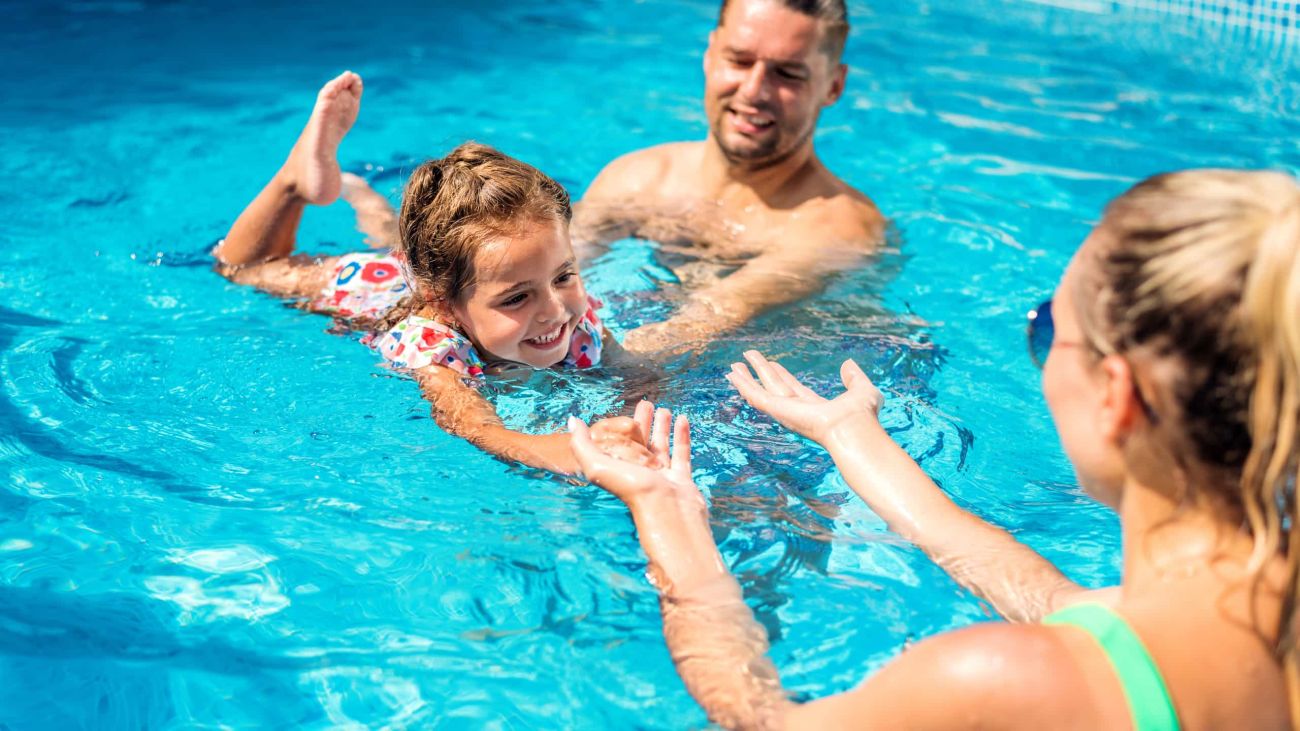 Familia disfrutando de un baño en piscina de magnesio con agua mineralizada pura y cristalina.